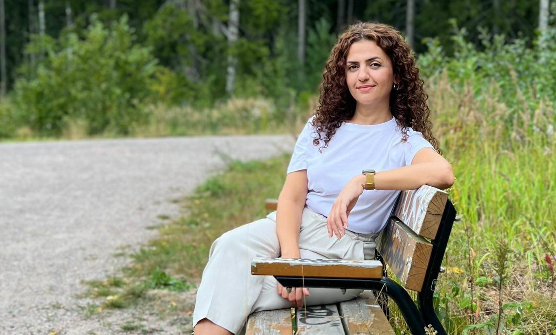 Gashaw Bibani istuu penkillä vehreässä ympäristössä. Hänellä on vaaleat vaatteet, tummat kiharat hiukset ja toinen käsi penkin selkänojalla.