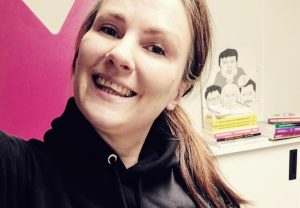 Kuvassa Milla Pyykkönen katsoo hymyillen kameraan. Yllään hänellä on musta huppari ja taustalla toimistotila.